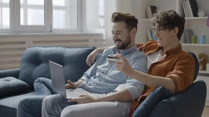 LGBT couple using credit card to make online payment on laptop, order services - Powered by Adobe