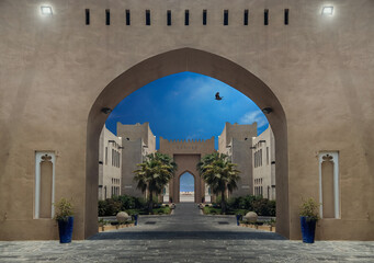 The illusion mirrored entrance gate with illuminated lights at dusk, with flying bird on blue sky in Katara cultural village,  valley of cultures in Doha, West Bay District, Qatar. Middle East, Arabia