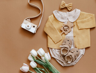 Baby clothes on brown background. Fashion baby outfit with tulips and booties. Top view, flat lay