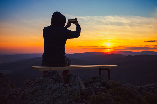 Man looking toward burning sunset sky and panoramic view of mountain hills