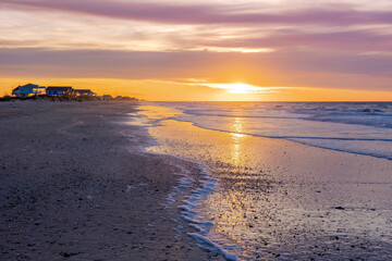 Summer time on the beach - sun rising on serene beautiful beach with beach houses in the distant 