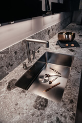 Dark expensive kitchen with built-in appliances. Brown veneer. Pots and pans.