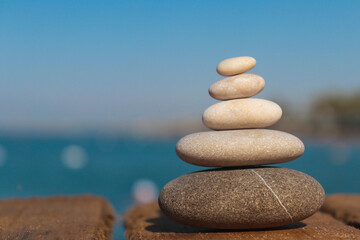 Fototapeta na wymiar Pyramid of stones by the sea with copy space. Zen concept. Blurred background. Concept of harmony, stability, life balance, and meditation. Summer mood