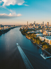 Sunset aerial shot of Brisbane as a City Cat heads towards the city on the Brisbane River - obrazy, fototapety, plakaty