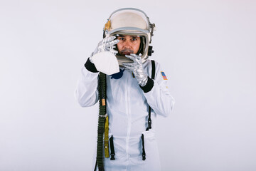 Male cosmonaut in spacesuit and helmet, holding a FPP2 mask, on white background. Covid-19 and virus concept