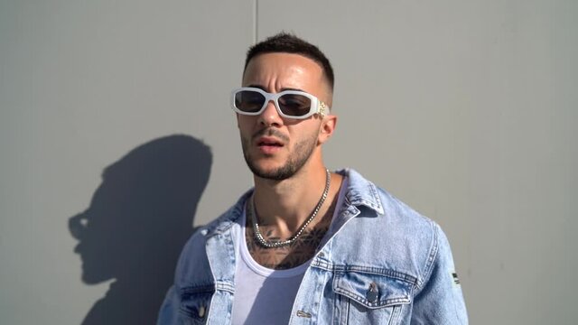 Chico movi&eacute;ndose yu posando delante de pared gris con el sol de lado ilumin&aacute;ndole