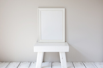 Minimalist vertical white frame mockup. Old wood floorboards and a rustic wooden stool.