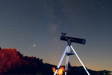 Black telescope reflector on a tripod in starry night sky scene. Observation of the night starry...