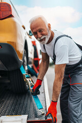 Handsome senior man working in towing service on the road. Roadside assistance concept..