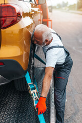 Handsome senior man working in towing service on the road. Roadside assistance concept..