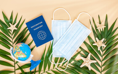 Vaccination or immunity passport, medical mask, globe, sea stars and palm leaves on neutral beige...