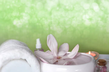 beautiful pink magnolia flower, smooth white stones in a stack, candles, white towel, concept of wellness spa treatments for the beauty of body and soul, massage, zen stone in the pool of serenity
