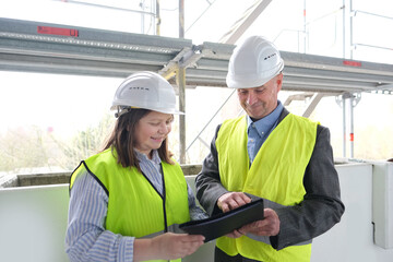 experienced elderly architect, female engineer constructor in protection of white helmet accept the object, sign documents at construction site, concept of civil engineering, cooperation