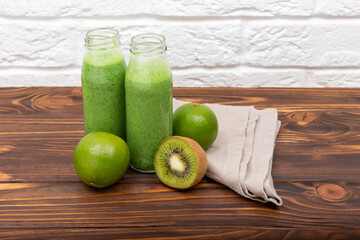 Jars of healthy green smoothie with fresh spinach. Fresh green smoothie on rustic wooden background. Vegetarian healthy green smoothie. Glasses with organic smoothie and straw. Detox diet concept