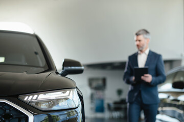 New cars in showroom. Dealership concept, focus on car on background car dealer using digital...
