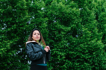 Naklejka premium Latin woman holding a leafy tree branch, looking at the camera. With a trees in the background. latino and nature concept. Copyspace