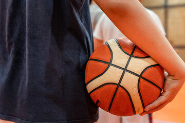 Close up on basketball ball in hands of unknown caucasian boy child teenager holding it on the...