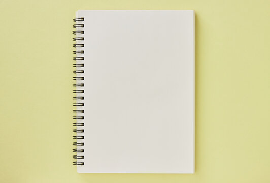 Spiral Notebook or Spring Notebook in Unlined Type on Pastel Yellow Minimalist Background. Spiral Notebook Mock up on Center Frame
