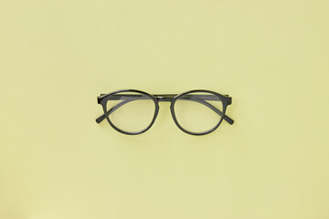 Top View Black Glasses on Pastel Yellow Minimalist Background