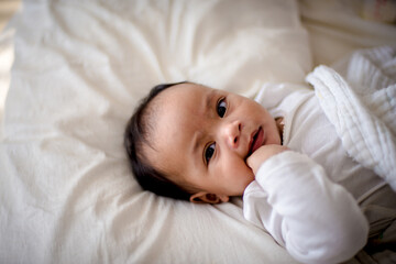 Infants are looking forward in an upside-down position on a white bed, the evolution of Baby girl in the age up to 6 months./Selected focus