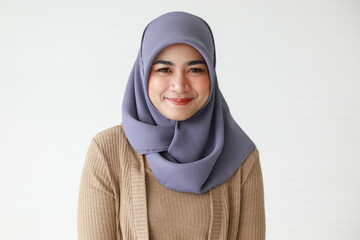 Confident young ethnic woman in Muslim headscarf smiling against white wall - obrazy, fototapety, plakaty