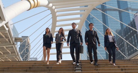 A group of business people of different ethnicities dressed in suits and ties walks proudly after leaving the offices. Concept of: team, success, connection and internationality.