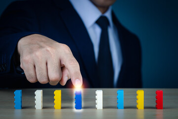 A man wearing a suit on his Right hand pointing to object on a table,concept is choose someone about business, blurred background.