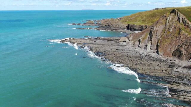 Aerial coastal shot of the waves in the sea at Spekes Mill beach in Devon
