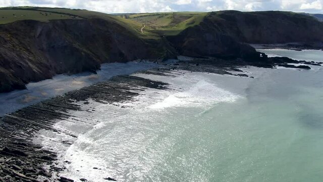 Aerial shot of the waves in the sea and the rocks at Spekes Mill coastal beach in Devon