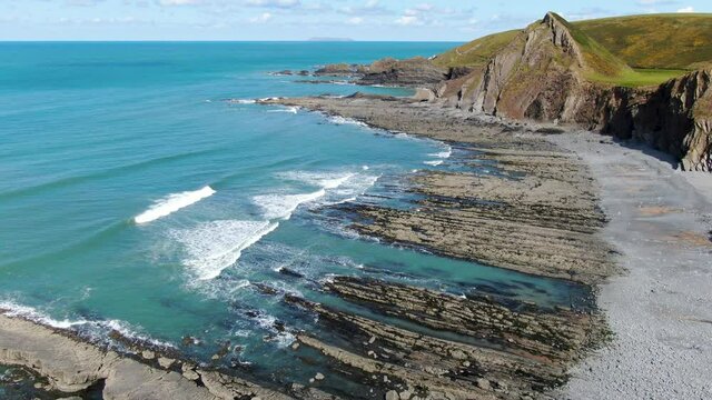 Aerial shot of the waves in the sea at Spekes Mill coastal beach in Devon on a sunny day