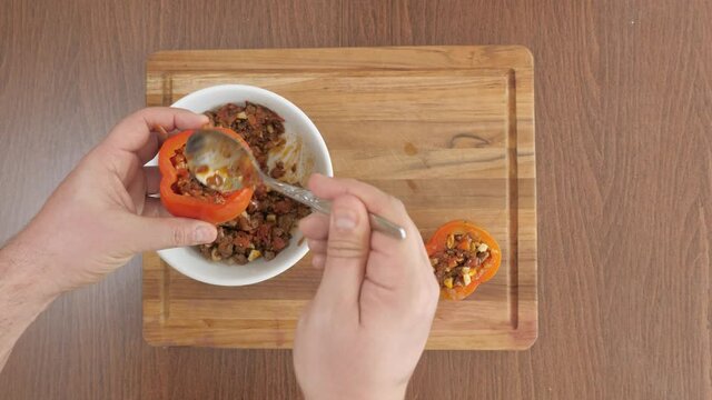 Man preparing traditional peruvian dish "Rocoto Relleno". Red hot pepper baked with meat mincemeat and species.