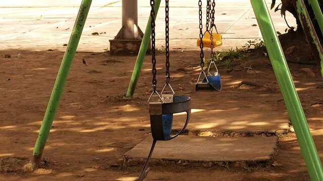 Set of kiddie swings at an old playground area inside a residential suburban subdivision in Mandaue City, Philippines.