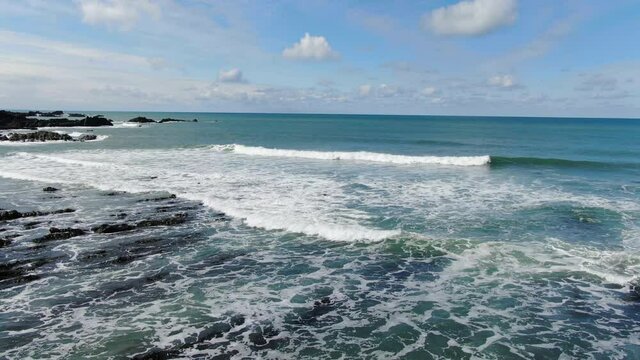 Aerial coastal shot of the waves crashing in the sea at Spekes Mill beach in Devon