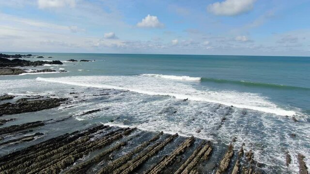 Aerial coastal shot of the waves in the sea at Spekes Mill beach in Devon, England,UK