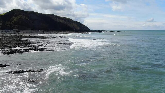 Aerial coastal shot in England of the waves in the sea at Spekes Mill beach in Devon