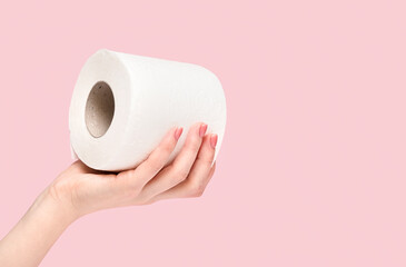 Toilet paper. Roll of paper in a female hand on a pink background.