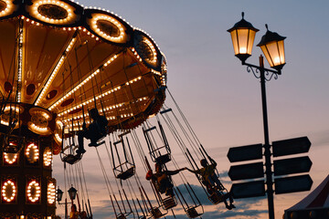 Children ride on the merry-go-round with swings. Silhouette of the carousel against the sunset
