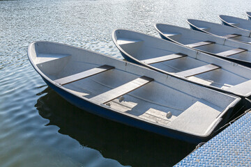 blue fiberglass boats are moored to the pier at the riverbank. rowboats for rental.