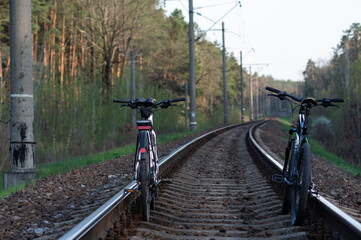Fototapeta na wymiar Two bicycles on the train tracks. Bicycles on rails. Trip around the world, Bicycles on the road in the forest.