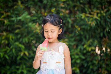 Close up footage of little girl eating ice pop in garden.