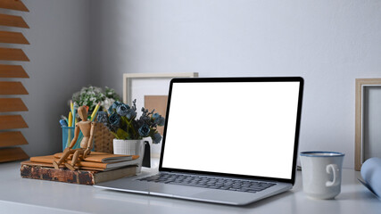 Close up mock up computer laptop, coffee cup and office supplies on white table.