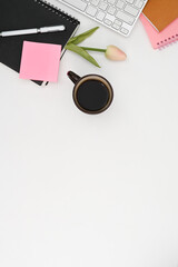 White desk with coffee cup, notebook, keyboard, pink tulip and copy space.