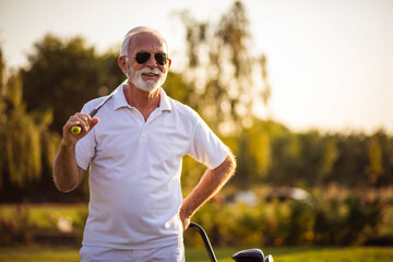 Smiling Senior golfer man standing on golf court.
