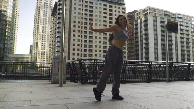 Young woman with brown hair dancing performing around big buildings in London slow motion