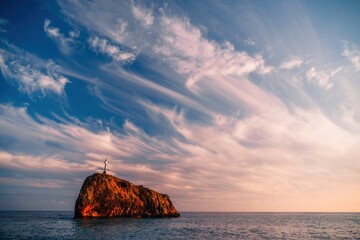 Bright sea sunset. The waves crash into the rock, lit by the warm sunset, sand and pebbles, volcanic basalt as in Iceland. Sea wave breaks into splashes and white foam. Never-ending beauty of nature