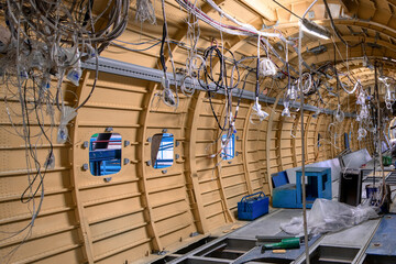 Construction of a new aircraft. Many electrical cables and wires hang from the sides of the fuselage