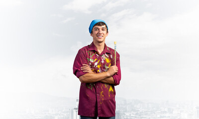 Smiling young painter artist holding paintbrush