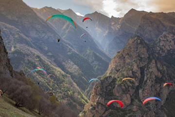 paragliders soaring among the mountains at sunset