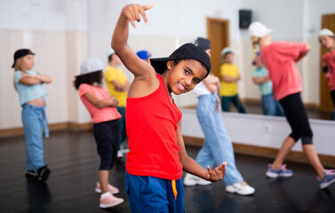 Fototapeta na wymiar Portrait of emotional african boy doing hip hop movements during group class in dance center