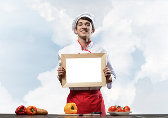 Young male chef standing near cooking table
